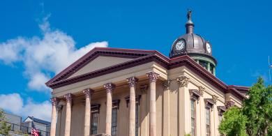 Historic building with clock tower against blue sky.