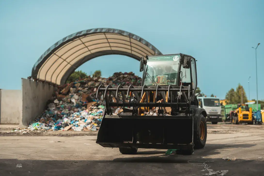 Front loader near a pile of recyclable materials under a shelter.